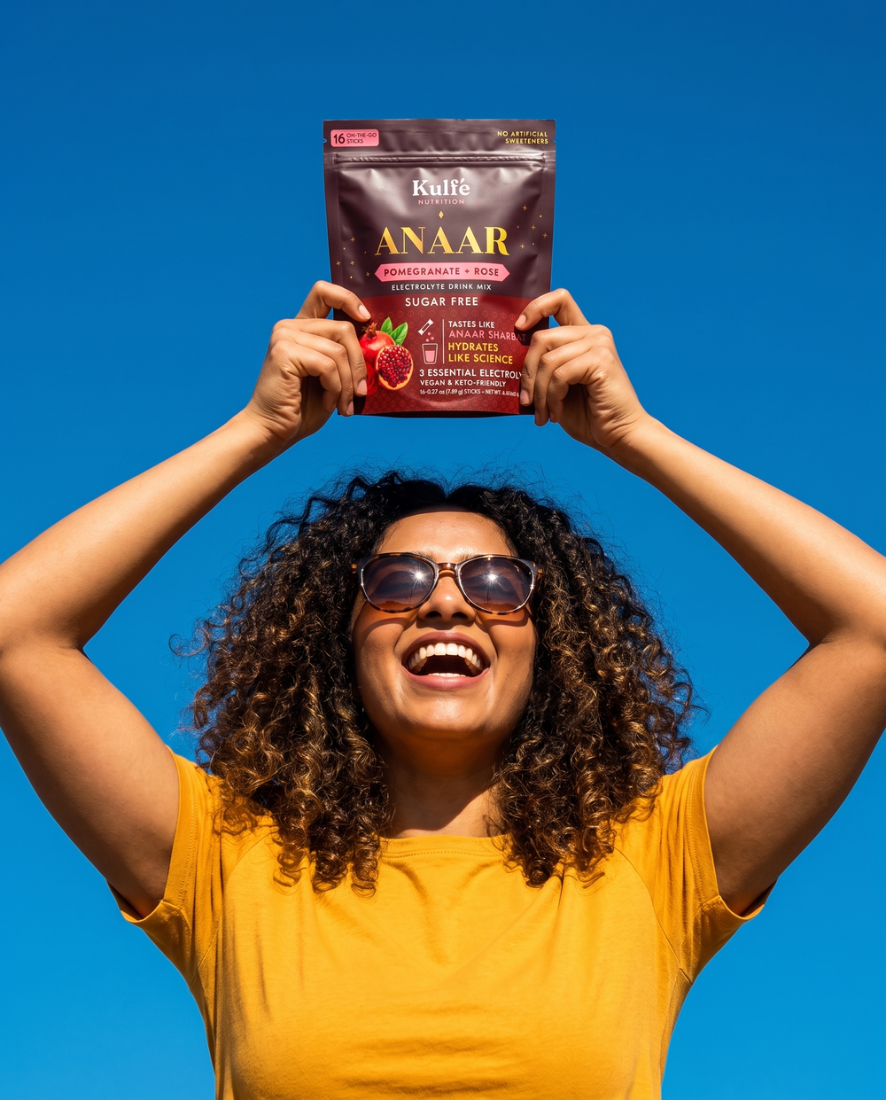 Kulfé customer holding an Anaar electrolyte pouch in the sun