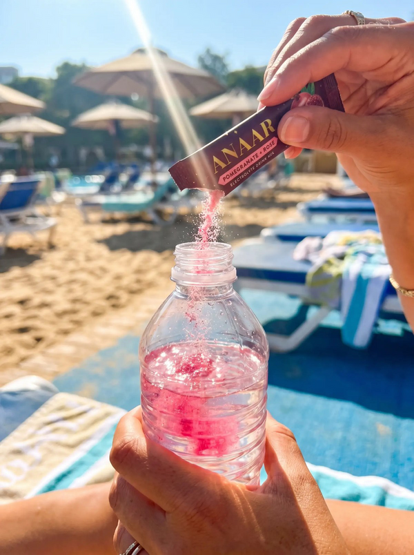 Anaar electrolyte stick poured into a water bottle at the beach